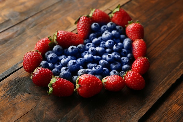 Fragole e mirtilli a forma di cuore su fondo di legno