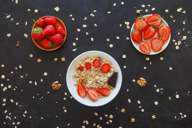 Fragole e muesli su un tavolo nero. Vista dall'alto.