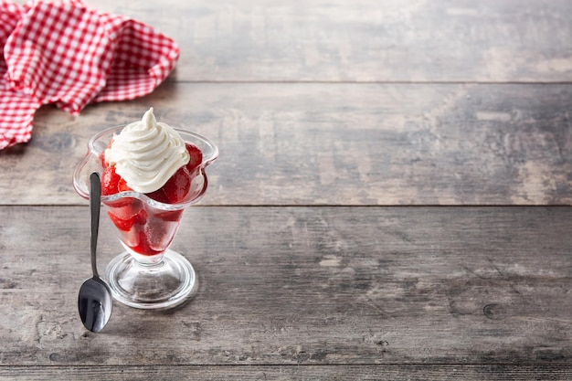 Fragole e panna montata in vetro gelato sulla tavola di legno