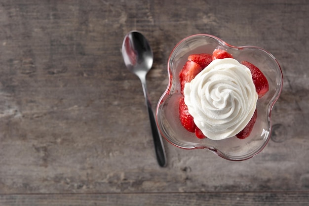 Fragole e panna montata in vetro gelato sulla tavola di legno