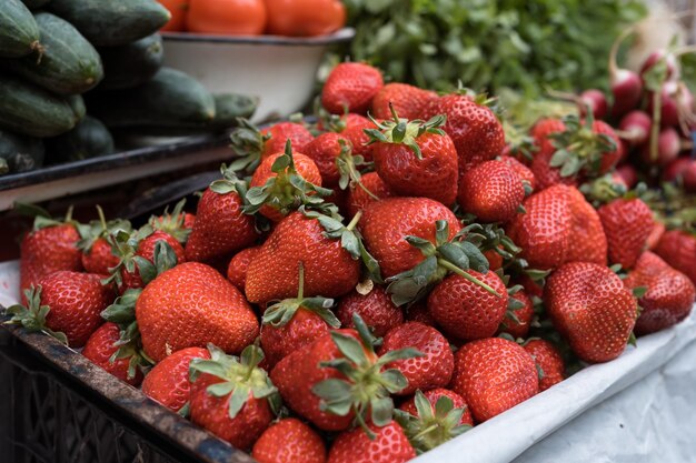 Fragole e verdure rosse fresche al mercato di strada