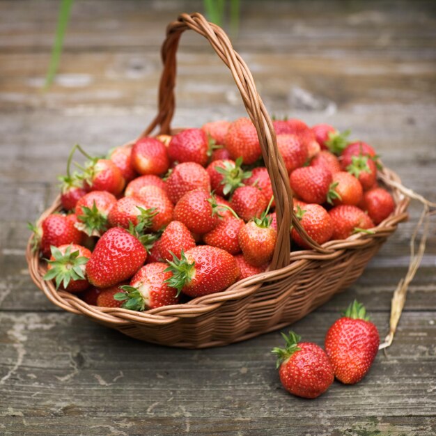 Fragole fresche in un cestino sul vecchio tavolo di legno, fuoco selettivo