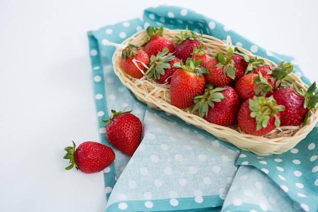 Fragole fresche nel vassoio di vimini su sfondo bianco