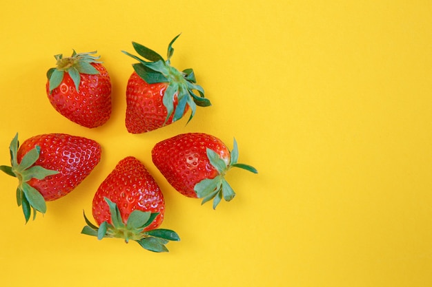 Fragole fresche saporite su colore giallo