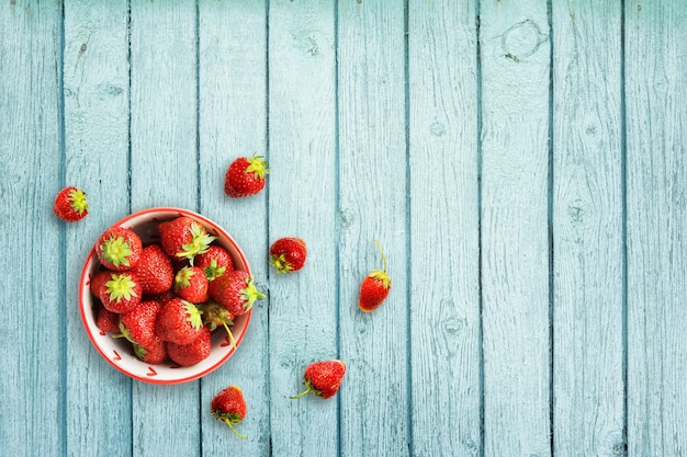 Fragole fresche su un fondo di legno cencioso blu.