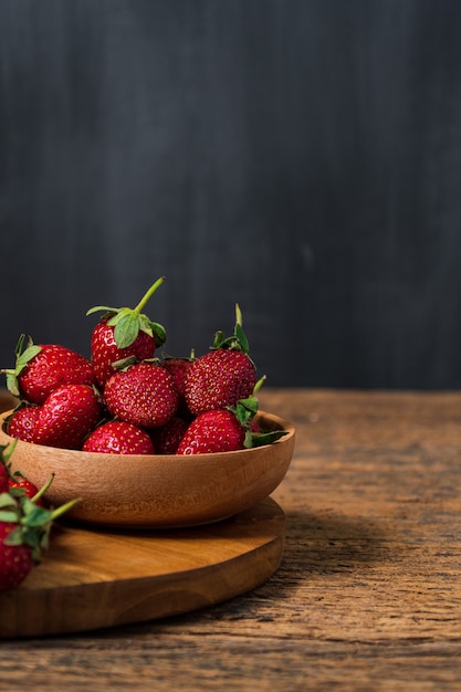 Fragole in ciotola di legno Sfondo di fragole Copyspace per il testo