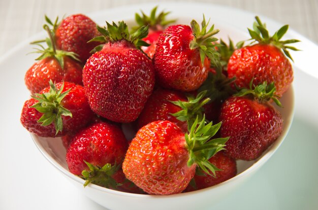 Fragole in un piatto bianco. Gruppo di fragole isolato su sfondo bianco