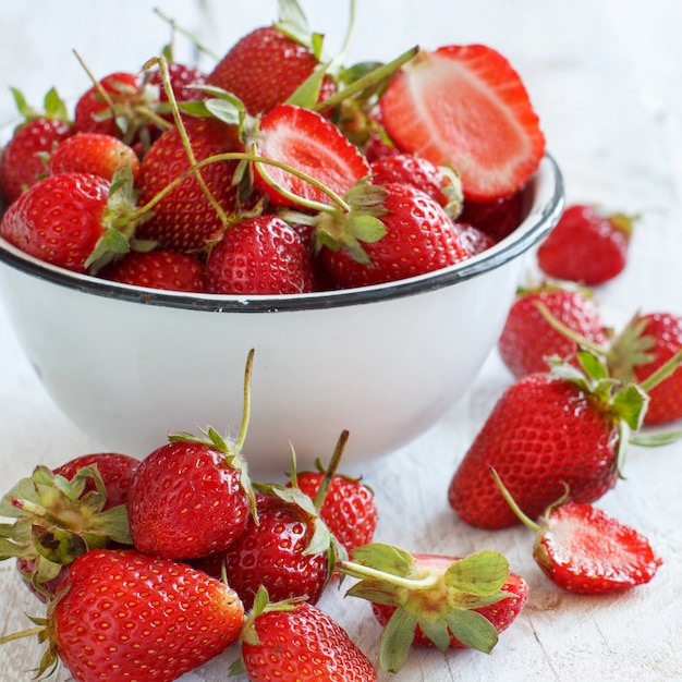 Fragole in una ciotola su un tavolo di legno bianco