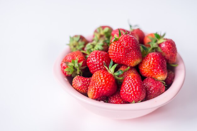 Fragole in una ciotola su uno spazio bianco