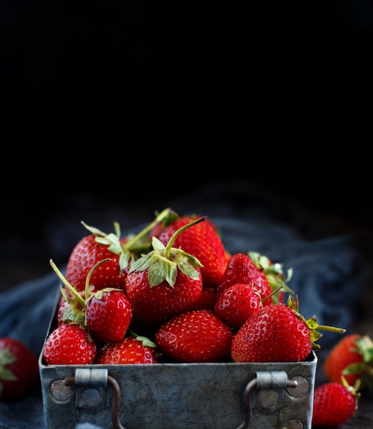 Fragole in una scatola su un tavolo di legno scuro