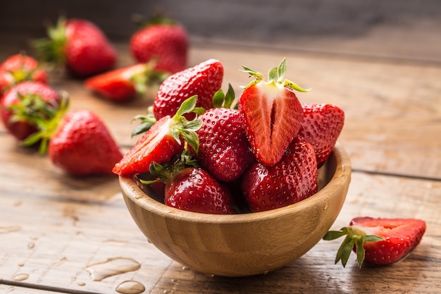 Fragole lavate succose in ciotola di legno sul tavolo da cucina.