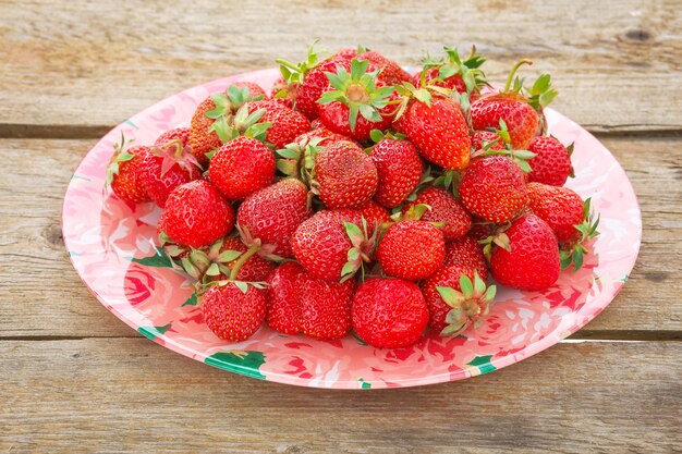 Fragole mature deliziose sul piatto, sulla tavola di legno.