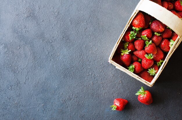 Fragole mature fresche in un cestino di legno su una priorità bassa scura