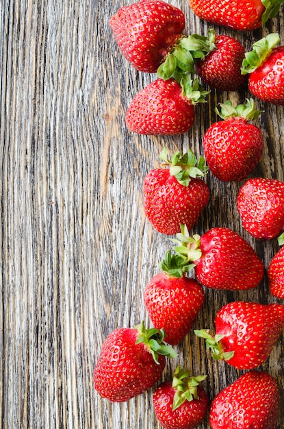 Fragole mature fresche su un fondo di legno. Bacche succose biologiche.