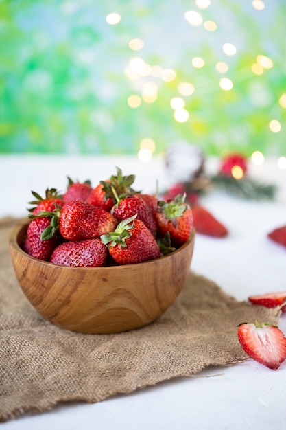 Fragole mature in una ciotola di legno su una tavola bianca