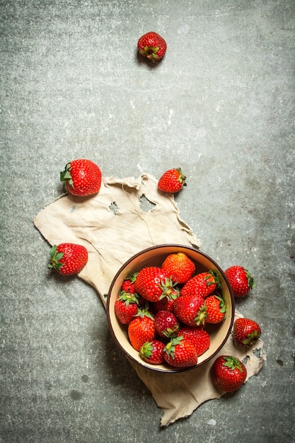 Fragole mature in una ciotola sul vecchio tessuto.