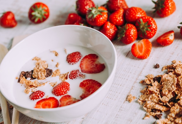 Fragole nel latte su un tavolo di legno. Colazione salutare