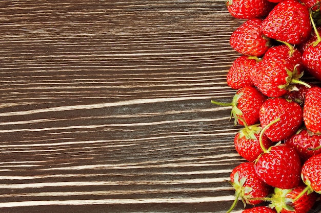 Fragole rosse fresche su un fondo di legno marrone