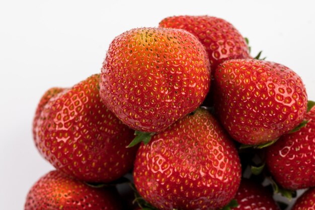 Fragole rosse mature e succose su fondo bianco.