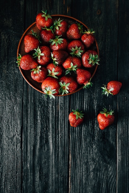 Fragole rosse mature su un piatto di legno