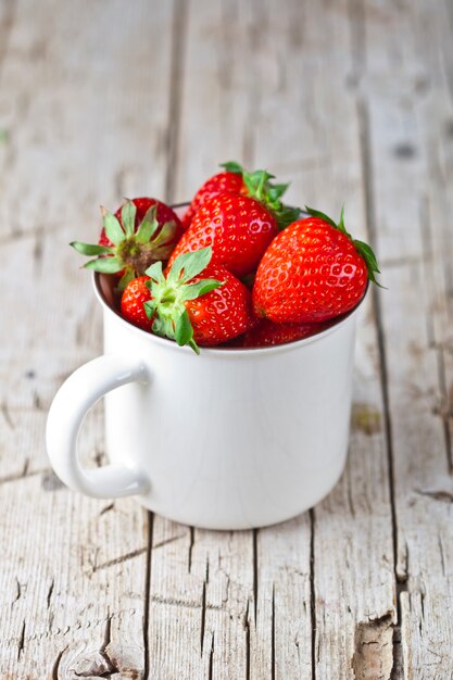 Fragole rosse organiche in tazza di ceramica bianca