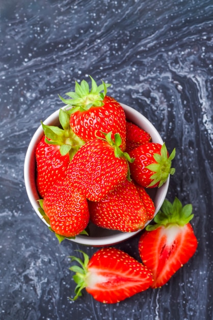 Fragole su fragole mature di marmo nero in un piattino su un posto nero del fondo per inserire il testo