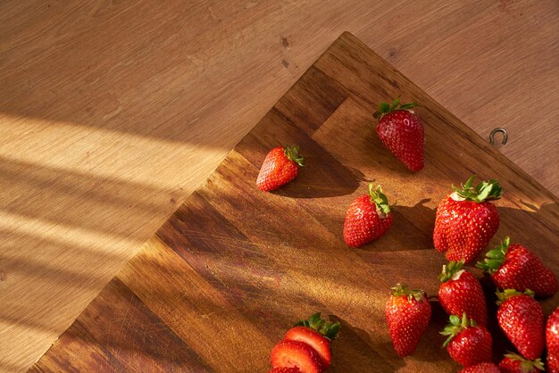 Fragole su un tagliere con un tavolo di legno sullo sfondo