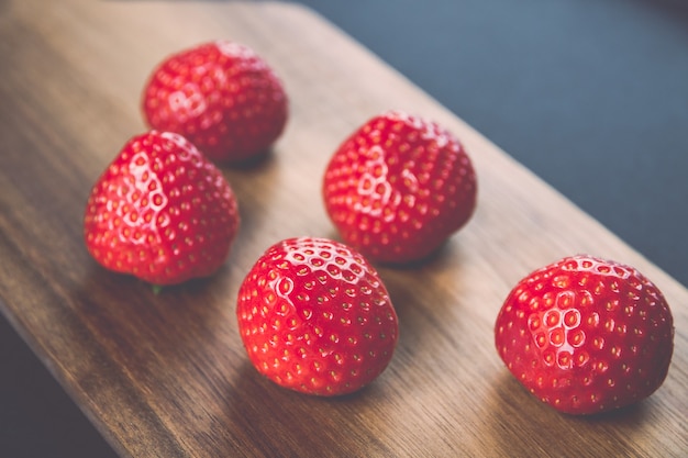 Fragole su un tagliere di legno. Sfondo nero