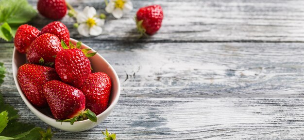 Fragole succose fresche con le foglie su una ciotola