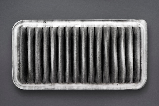 Frammento dettagliato del filtro dell'aria sporco su sfondo grigio