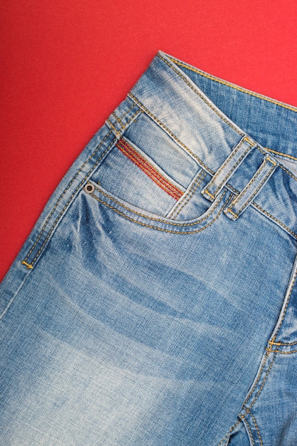 Frammento di jeans squallido azzurro su superficie rossa