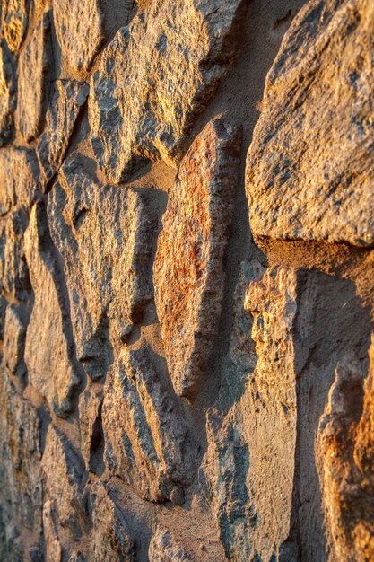 Frammento di muro di pietra illuminato dal sole al tramonto. Vista laterale con profondità di campo ridotta