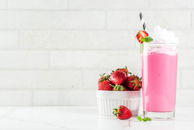 Frappè freddo della fragola con le bacche e la menta fresche su fondo di marmo bianco