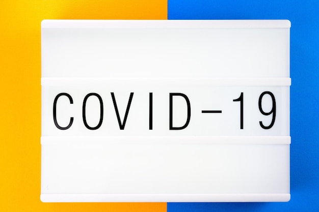 Frase Covid19 scritta su uno striscione bianco con sfondo colorato