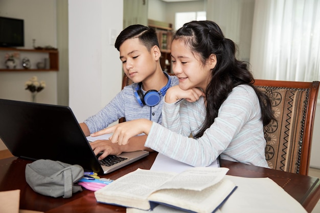 Fratelli adolescenti che studiano a casa a causa del blocco stanno guardando insieme le lezioni online