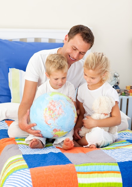 Fratelli biondi e il loro padre guardando un globo terrestre