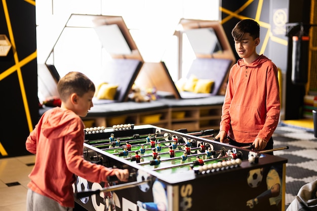 Fratelli che giocano a calcio balilla nel centro giochi per bambini