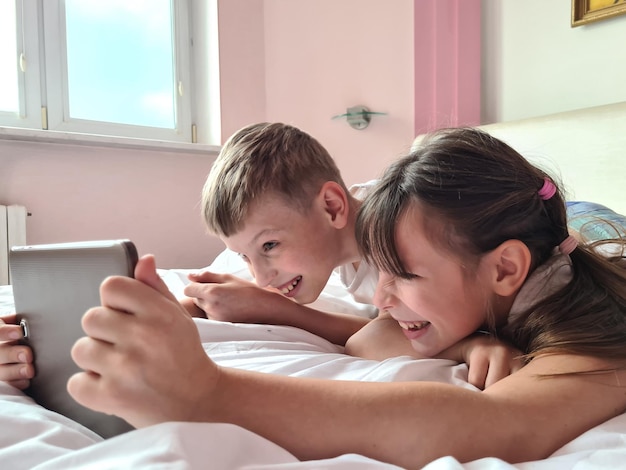 Fratelli e sorelle felici si sdraiano sul divano di casa e giocano insieme con il tablet