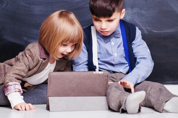 Fratelli felici che usano il tablet PC e giocano insieme Bambini a casa