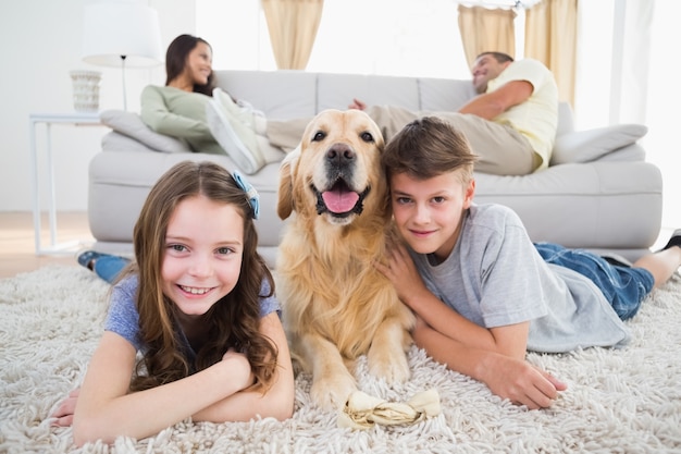 Fratelli germani che si trovano con il cane mentre i genitori appoggiano sul divano