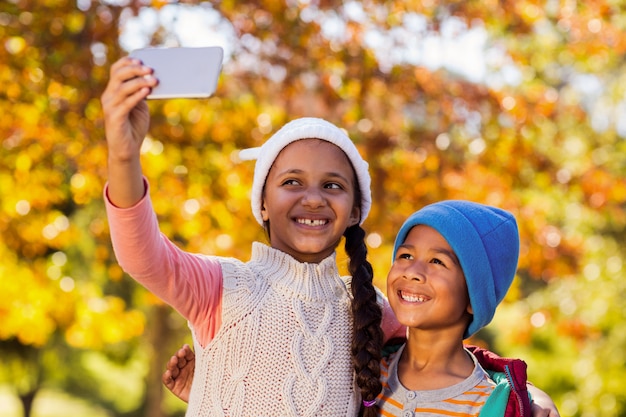 Fratelli germani sorridenti che prendono selfie al parco