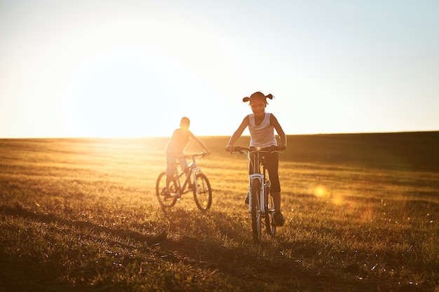 Fratelli in bicicletta sul campo contro il cielo durante il tramonto