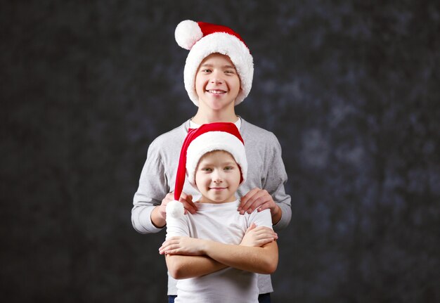 Fratelli in cappelli di Babbo Natale su sfondo grigio