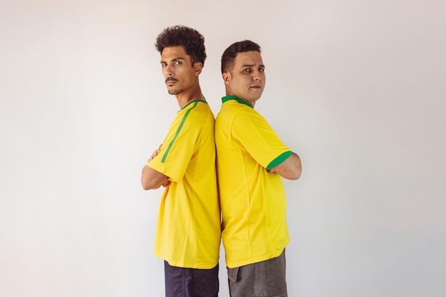 Fratelli neri con camicia brasiliana gialla e bandiera tifo isolati su bianco
