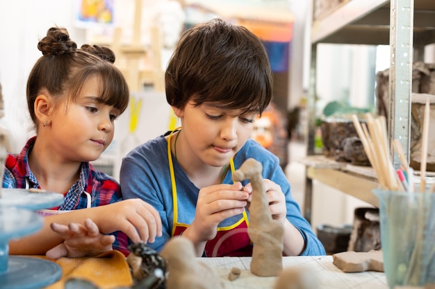 Fratello e sorella alla lezione di arte modellando animali di argilla