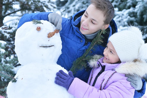 Fratello e sorella che fanno un pupazzo di neve all'aperto in inverno