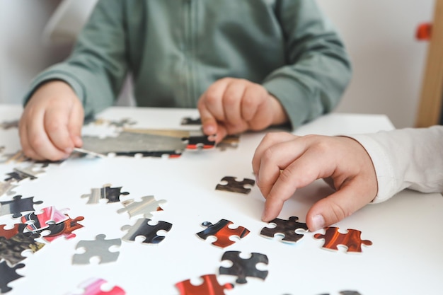 Fratello e sorella che giocano a puzzle a casa Bambini che uniscono i pezzi di un puzzle in un tavolo del salotto Bambini che assemblano un puzzle Divertimento per il tempo libero in famiglia