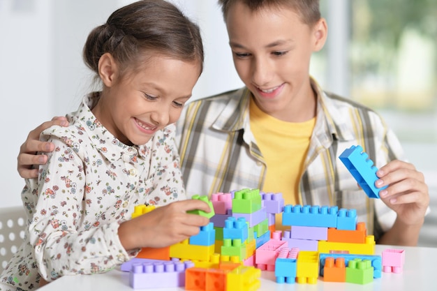 Fratello e sorella che giocano insieme con blocchi di plastica colorati