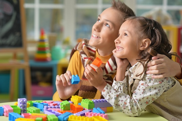 Fratello e sorella che giocano insieme con i blocchi di plastica colorati