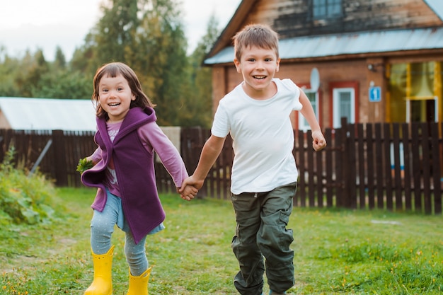 Fratello e sorella corrono per mano nella casa del villaggio. vacanze al villaggio con mia nonna.